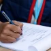 Close-up of female courier writing delivery list before the shipment.
